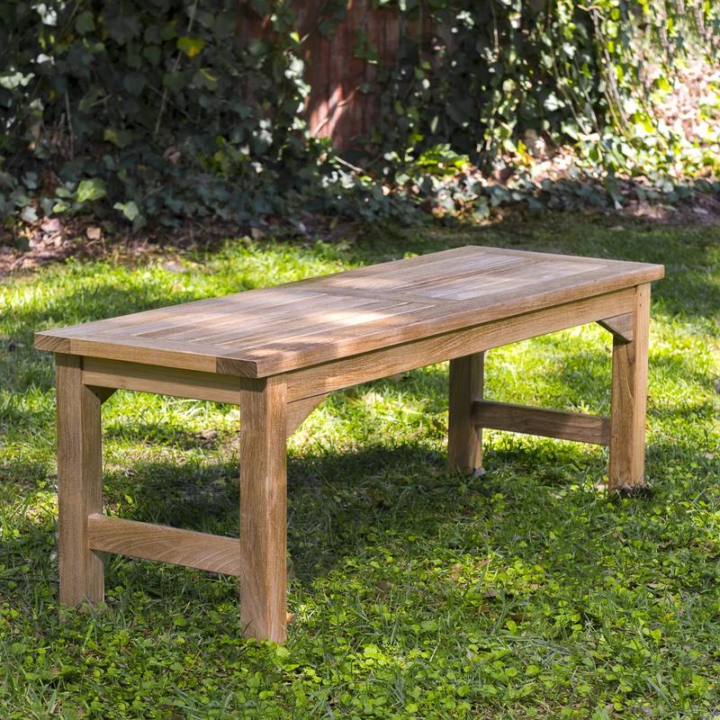 alt="13940 Veranda 4 foot Teak Backless Bench angled end view on grass area with trees & shrubs in background"