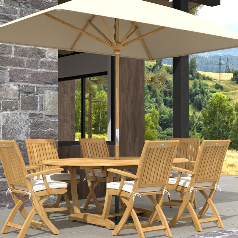 alt="70368 Martinique Oval Barbuda Chair 7 pc Dining Set with optional umbrella and optional seat cushions in angled view on outdoor patio next to stone house with trees in background "