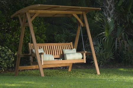 alt="13955 veranda teak swinging bench and canopy set angled front view on grass lawn with trees and shrubs in background"