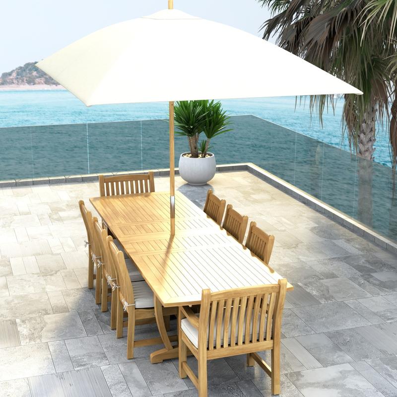 alt="70792 Veranda 9 pc Teak Dining Set with optional seat cushions and umbrella in aerial end view showing a potted plant and ocean view in background "