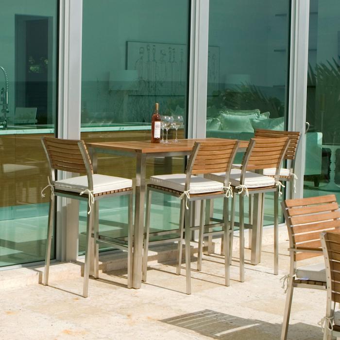 alt="25314 Vogue 5 foot Rectangular Bar Set with optional seat cushions bottle of wine and 3 wine glasses on table set on concrete patio with glass sliding doors in background"