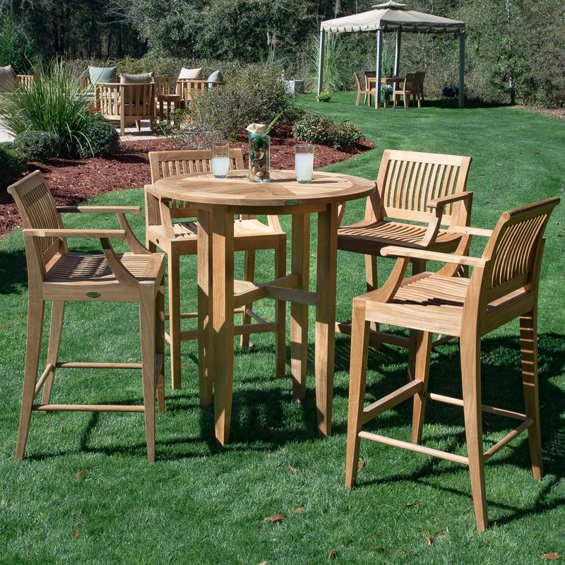 alt="70294 Laguna 5 piece teak Round Bar Table Set on grass lawn with vase centerpiece and two lemonade glasses on table with gazebo and landscape plants in background  "