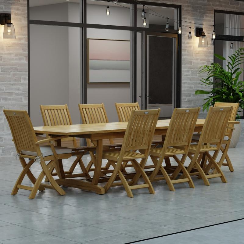 alt="70794 Veranda Barbuda Teak 9 pc Dining Set of Grand Veranda Dining Table and 2 Barbuda Armchairs and 6 Side Chairs angled side view on a patio with patio lights and glass doors in background"