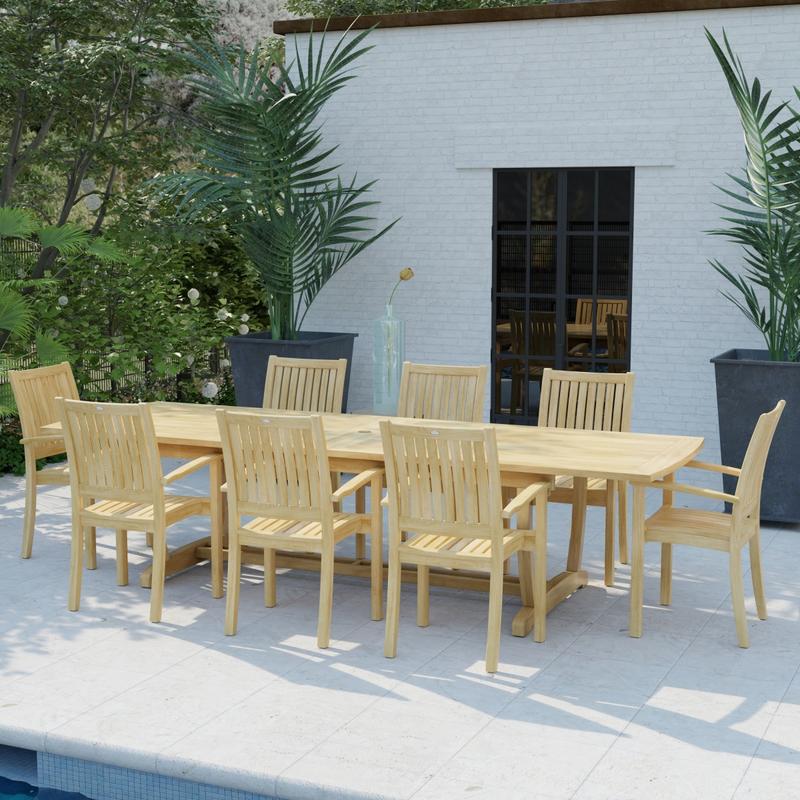 alt="70759 Sussex Veranda 9 pc Teak Patio Dining Set in angled side view on pool deck behind a pool with house and windows and 2 potted plants in background "
