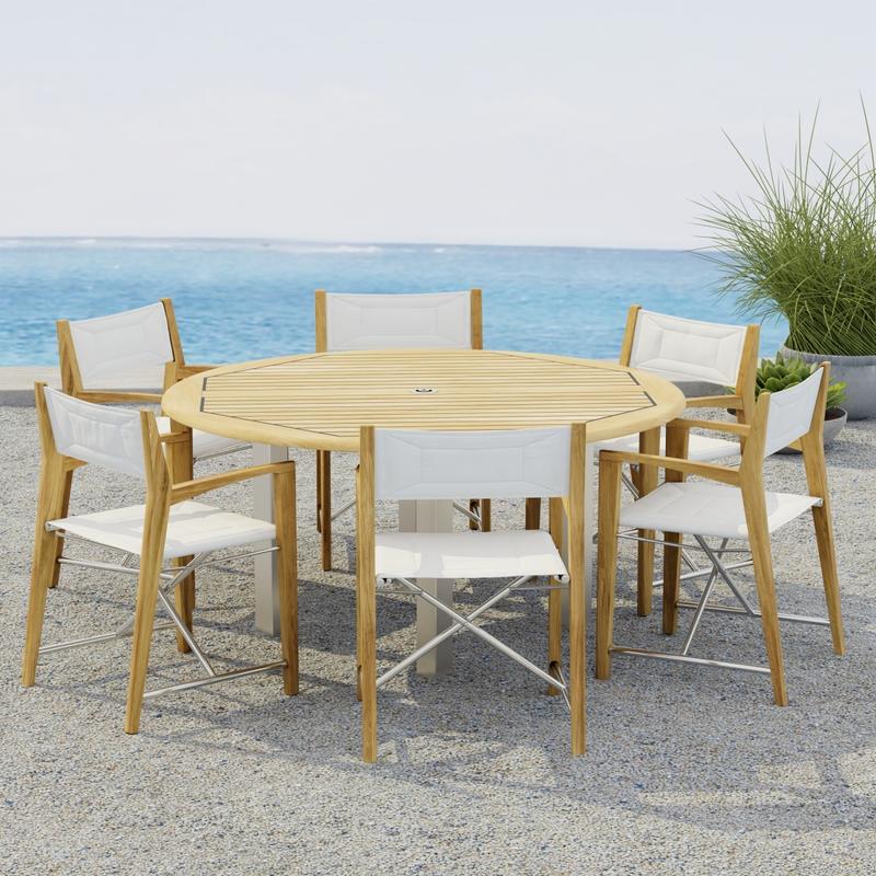alt="70359  Vogue Odyssey 7 pc Dining Set showing Vogue 5 ft Round Table and 6 Odyssey Chairs on terrace angled side view with 2 potted plants and ocean in the background"