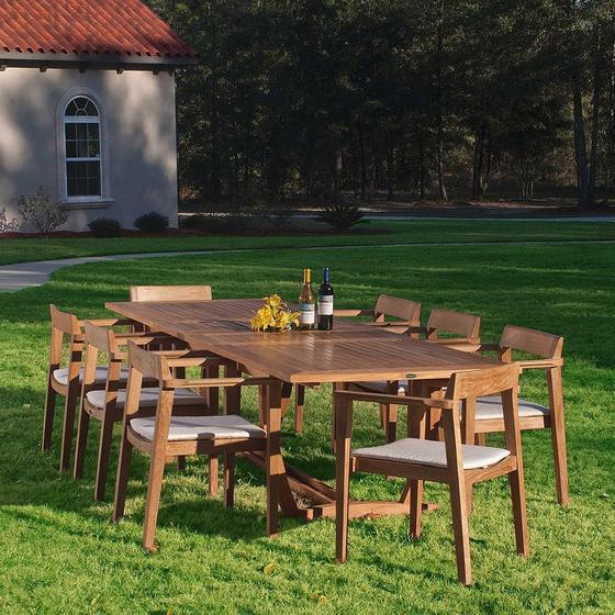 70237 Grand Horizon teak 9 piece Dining Set with optional canvas colored cushions yellow flowers two wine bottles on grass lawn house and landscaped background