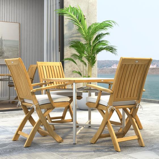 70577 Barbuda Odyssey Folding Dining Set  of Odyssey Table and 4 Barbuda Folding Chairs with optional cushions in side view on stone patio in front of glass door and potted plant and ocean in background  