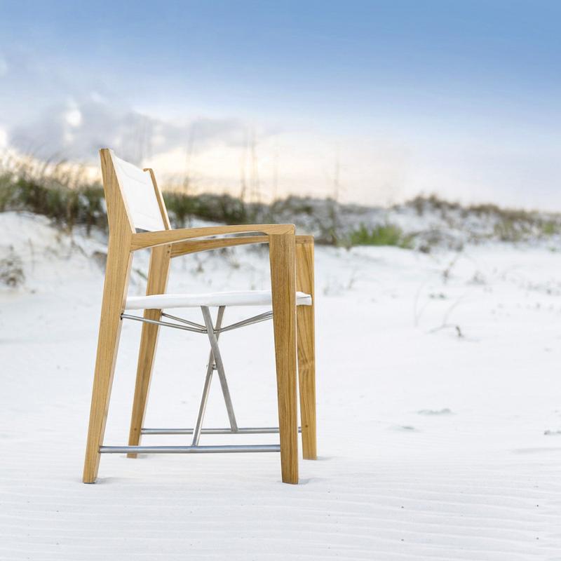 alt="12915F Odyssey Director Chair right side view facing ocean on sandy beach with sand dunes and sea grass and blue sky in background"