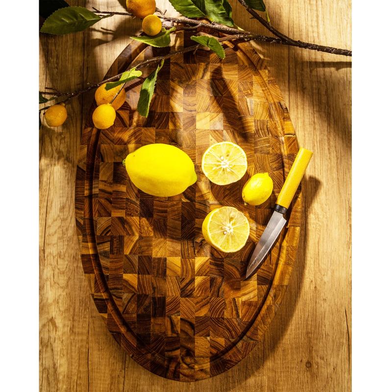 alt="19125 Butcher Block 20 inch Oval Charcuterie Cutting Board with 2 lemons and a knife showing aerial view of the cutting board on a countertop"