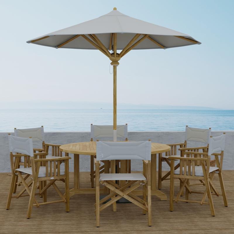 alt="70362 Barbuda Director 7 piece Teak Dining Set of 6 Director Chairs and Round 60 inch diameter folding teak dining table with optional opened umbrella side view with ocean background  "