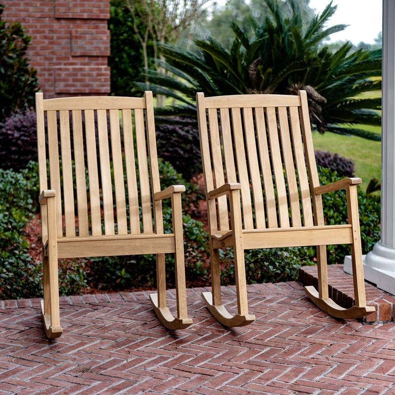 alt="70912 veranda teak rocker chat set next to white pillar on red brick porch with shrubs grass and brick wall in background"