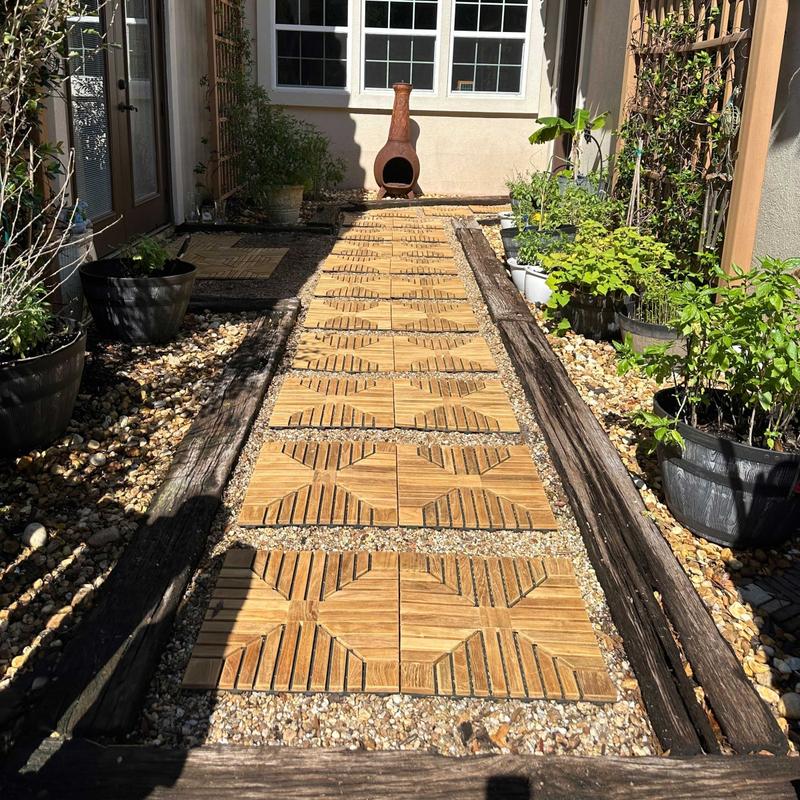 alt=" 18408P diamond teak tiles installed on a walkway surrounded with landscaping plants and 2 trellises with chimenea and house in background  "