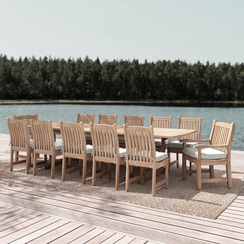 alt="70017 Grand Veranda 13 piece dining set with optional seat cushions in angled side view on wood deck with water and trees in background "