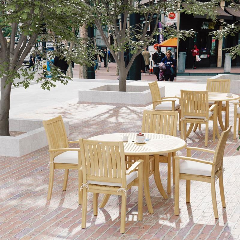 alt="70027 Grand Hyatt 5 pc Dining Set on brick patio showing 2 with table settings with optional seat cushions outdoors with landscape trees and people and store fronts in background"
