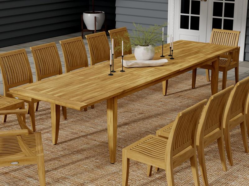 alt="15978  laguna teak extension table with 6 candlestick holders and potted plant with 10 side chairs angled side view on patio with house in background"
