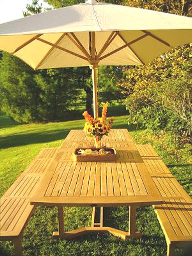 alt="70065 Grand Veranda teak Picnic Bench Set with optional open market umbrella and flowers in vase woven basket on grass lawn landscape plants and tree in background"