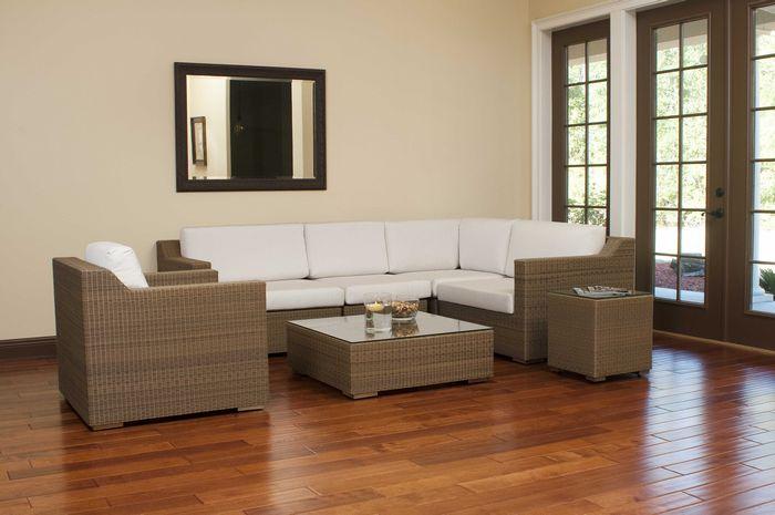 alt="31004 malaga synthetic wicker collection indoor angle view on wood floors wall mirror behind sofa bowl and floating candle on table with french doors overlooking patio"