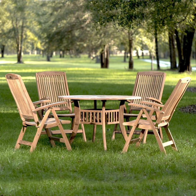 alt="70045 Hyatt Recliner 5 piece round teak Dining Set of 4 teak reclining armchairs and a round 48 inch diameter dining table on grass field with background of trees in distance"
