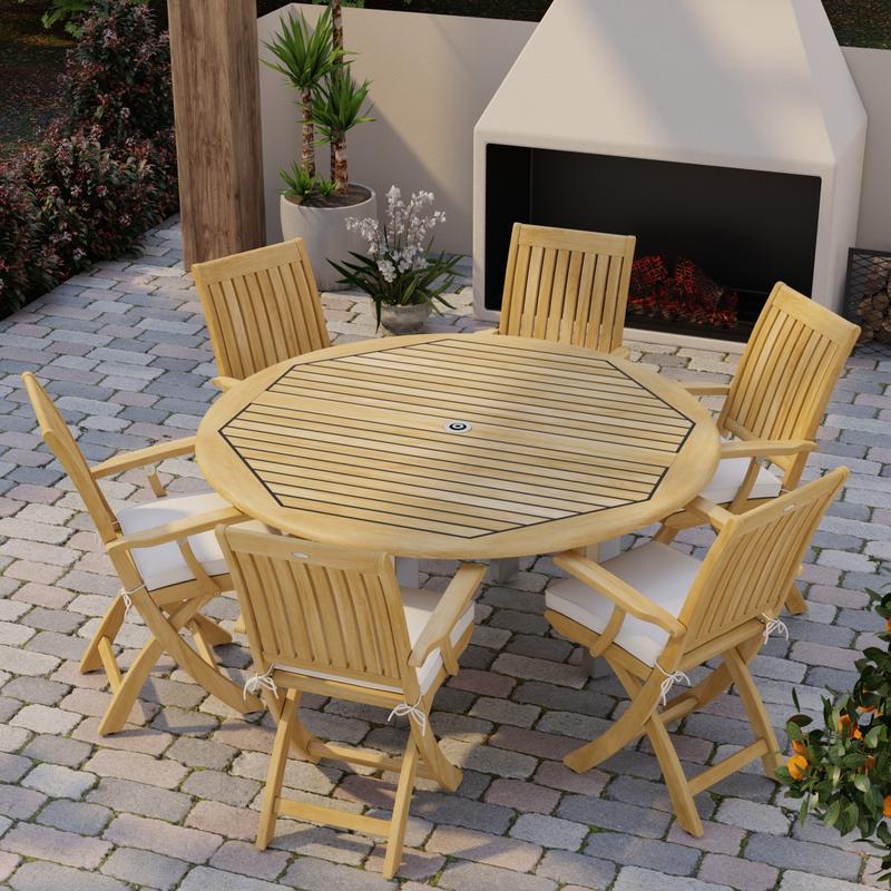 alt="70357 Vogue Barbuda 7 pc Dining Set angled aerial view of table top on brick paver patio in front of an outdoor fireplace and landscape plants in background"