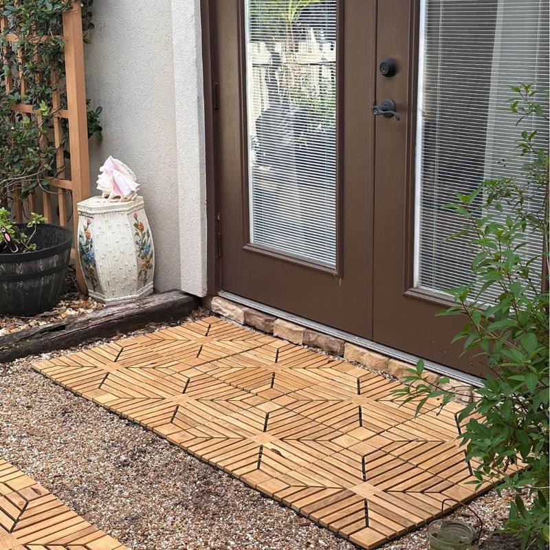 alt="18408P diamond teak tiles showing 8 on rocks assembled together in front of French doors with landscaping ornaments and plants in background "