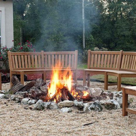 alt="70862 Buckingham teak 6ft curved bench set of 2 around fire pit with trees in background"
