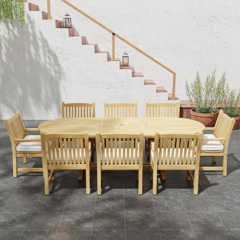 alt="70178 Montserrat Veranda Teak 9 pc Dining Set of Montserrat Dining Table and 8 Veranda Side Chairs in side view on patio with potted plant and staircase of house in the background"