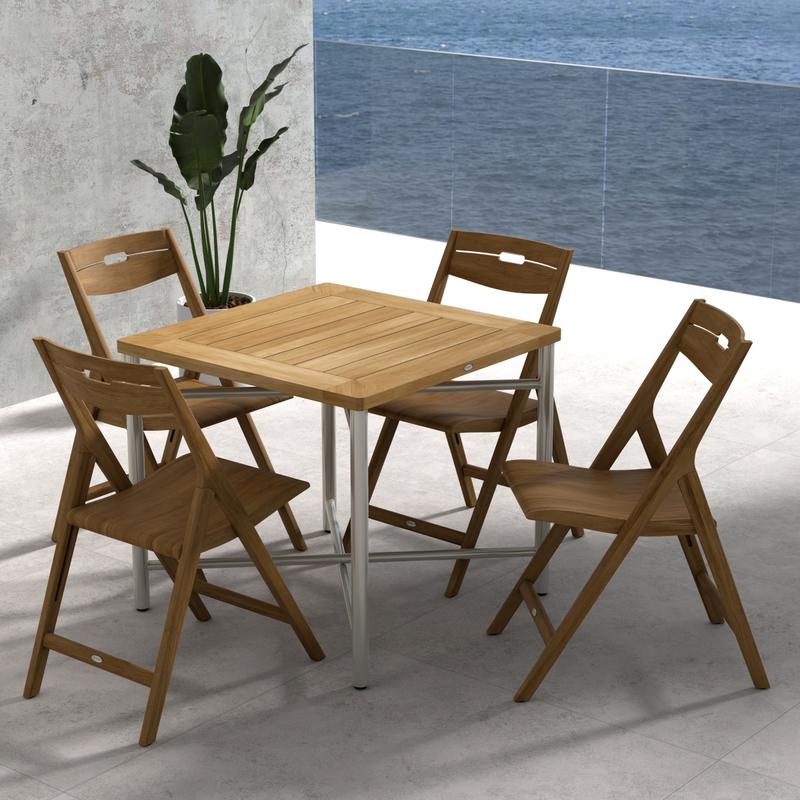 alt="70450 Surf Odyssey Folding Dining Set of Odyssey Bistro Table and 4 Surf Side Chairs in angled aerial view on a stone patio with the ocean and blue sky in the background"