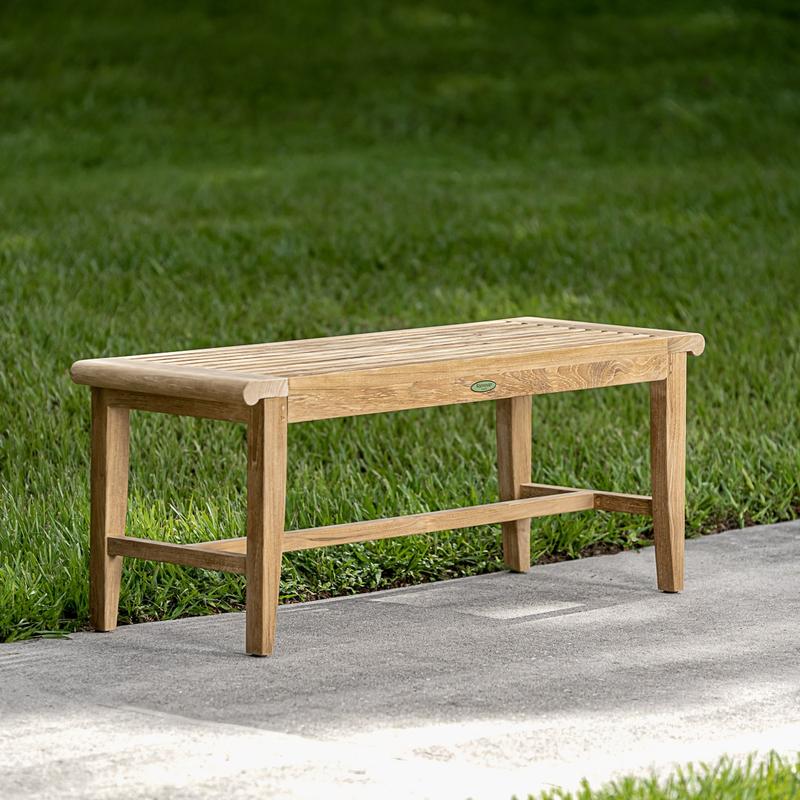 alt="13915 Laguna 4 foot long teak Backless Bench on concrete walkway with grass in background"