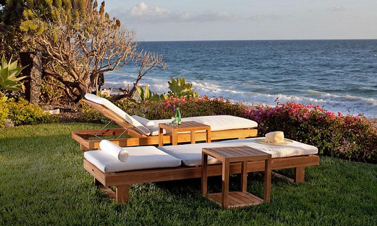 alt="16770 Horizon Teak Chaise Loungers showing 2 loungers with one reclined flat one back inclined with 2 side tables on grass with landscape plants facing ocean and blue sky background "