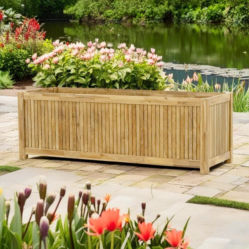 alt="18131 rectangular five foot planter angled side view on paver walkway surrounded by landscaping plants with lake and shrubs in background"