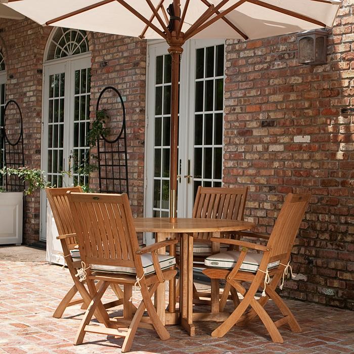 alt="70066 Barbuda Round 5 piece Folding Dining Set on brick patio showing optional open umbrella in table with house and french patio doors in background"