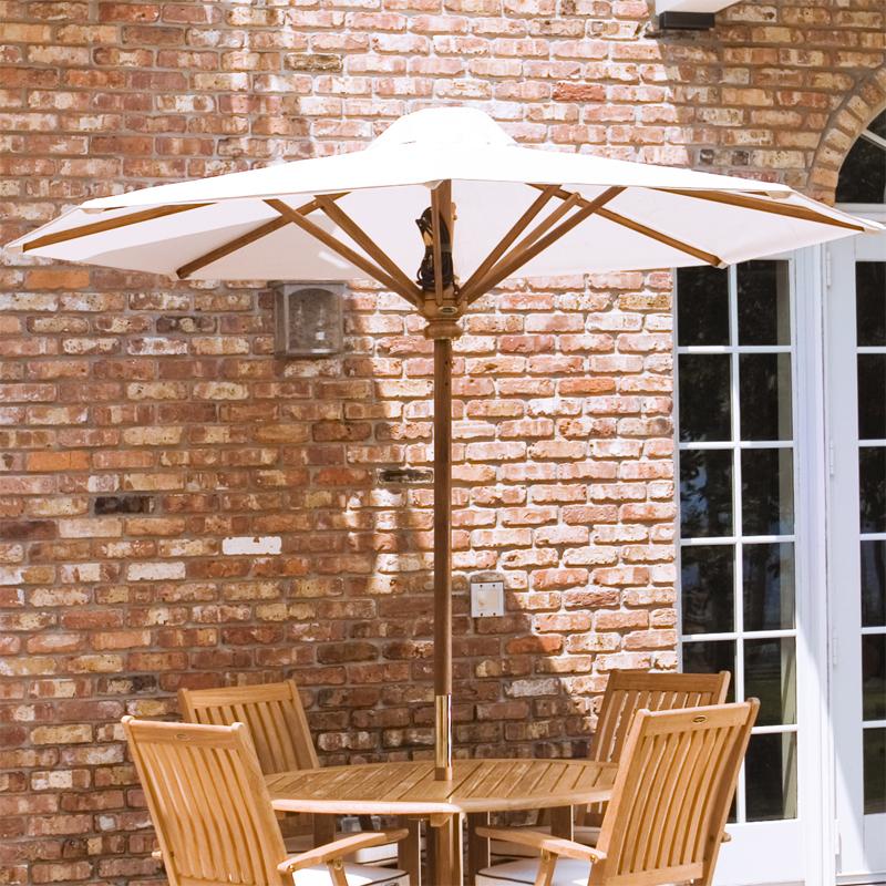 alt="17540F Somerset 8 foot Round teak Umbrella extended on round patio set next to brick house and french doors in background"