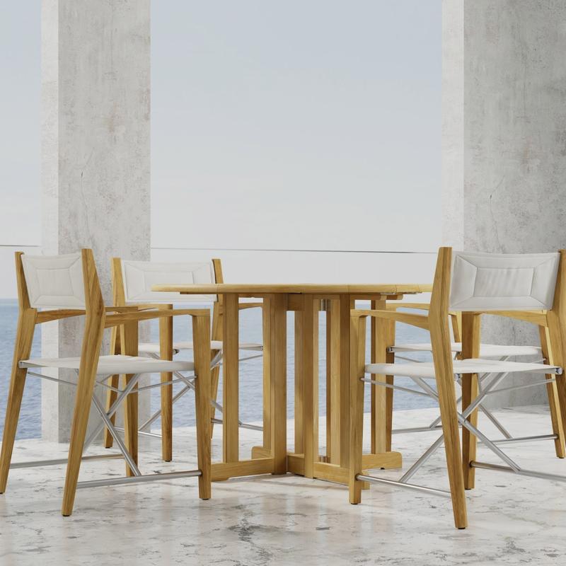 alt="70473 Odyssey Barbuda 5 piece Folding Dining Set of 4 folding director chairs and 48 inch round teak table on marble patio with ocean and sky in the background"