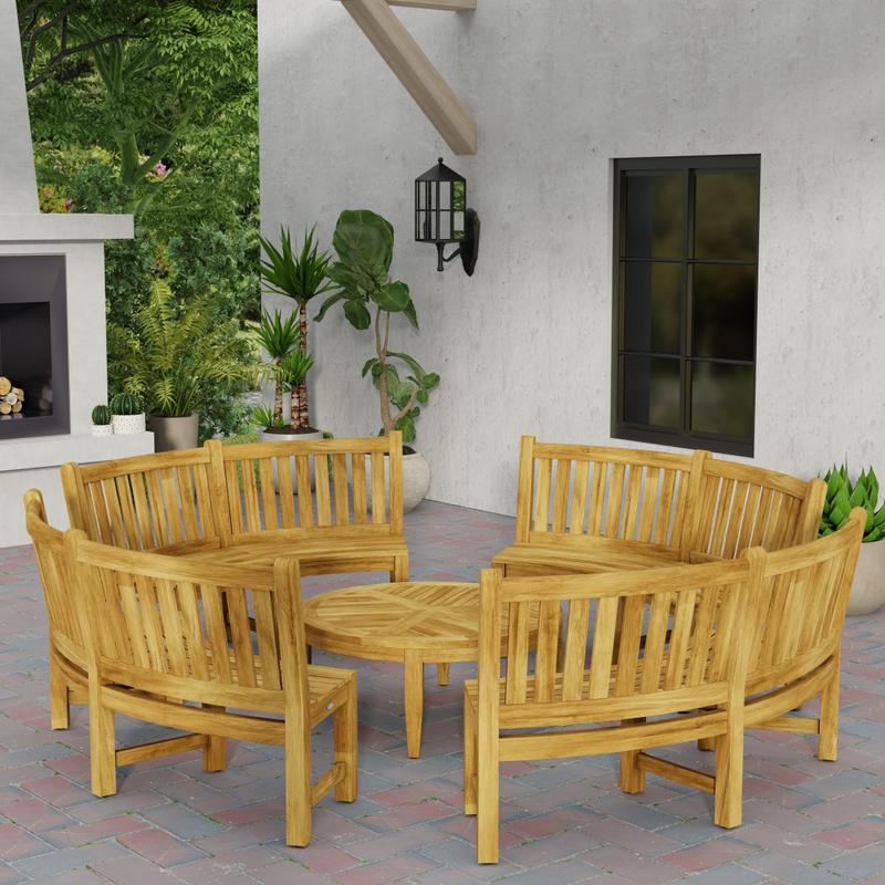 alt="70862 Buckingham teak 6ft curved bench set of 4 in circle around the Laguna Coffee Table in side angled view on patio next to a fireplace with 4 potted plants in background "
