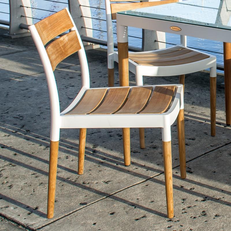alt="70591 Bloom teak and powder coated aluminum side chair angled side view on wooden dock with marina background"