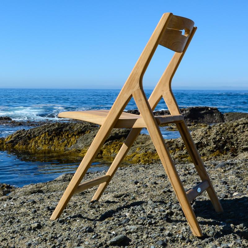 alt="70589 Vogue Surf teak folding side chair on sandy beach facing ocean and blue sky"