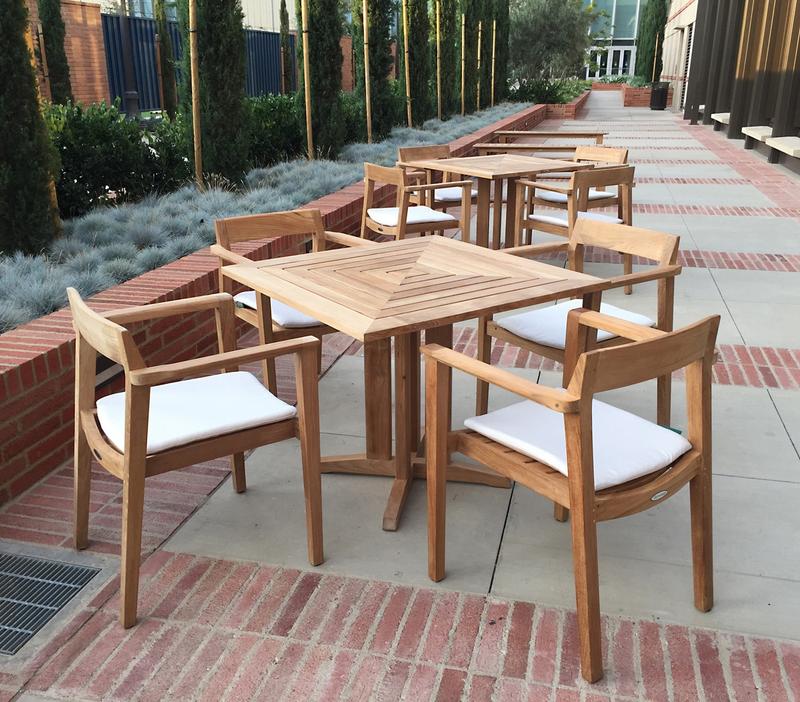alt="12901 Horizon teak armchair with 5 piece Pyramid Dining Set showing optional seat cushions on stone patio in front of restaurant"