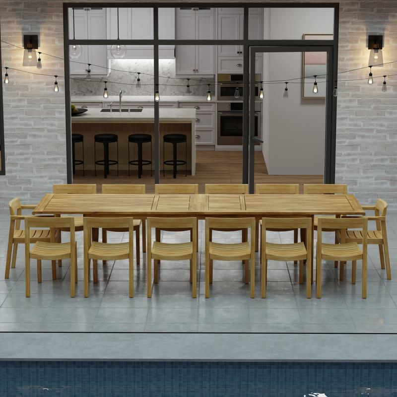 alt="70353 Laguna 15 pc Teak Dining Set of 14 dining armchair and rectangular 11 foot extendable dining table side view in front of glass doors in the background  "