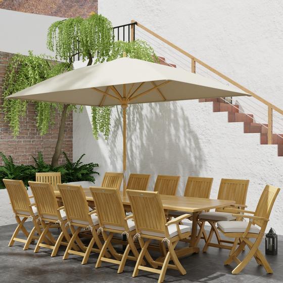 70095 Barbuda Teak 13 pc Patio Set with optional umbrella in angled side view next to a planter with a tree and plants and a staircase in background