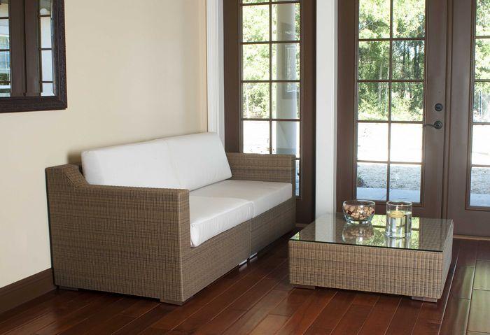 alt="31004 malaga synthetic wicker deep seating sectional side view on wood floors wall mirror behind sofa bowl and floating candle on table with french doors overlooking patio "