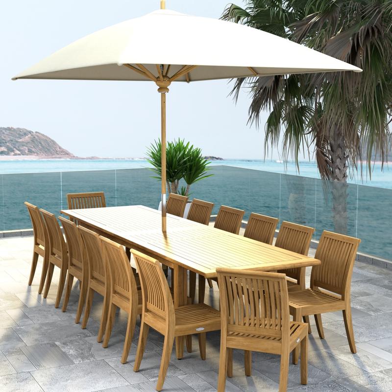 alt="70917 Laguna 15 pc Teak Dining Set with optional umbrella in angled end view on tiled patio with palm tree and ocean in background"