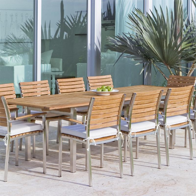 alt="22007ST Vogue 11 piece  Armchair Dining Set with optional seat cushions on concrete patio with glass sliding doors in background"