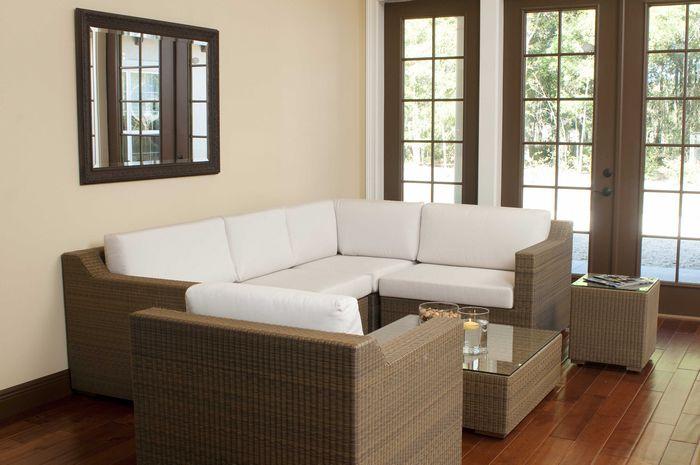 alt="31002 malaga synthetic wicker deep seating collection side view on wood floors wall mirror above sofa floating candle bowl of snacks magazine on table with windows overlooking yard  "