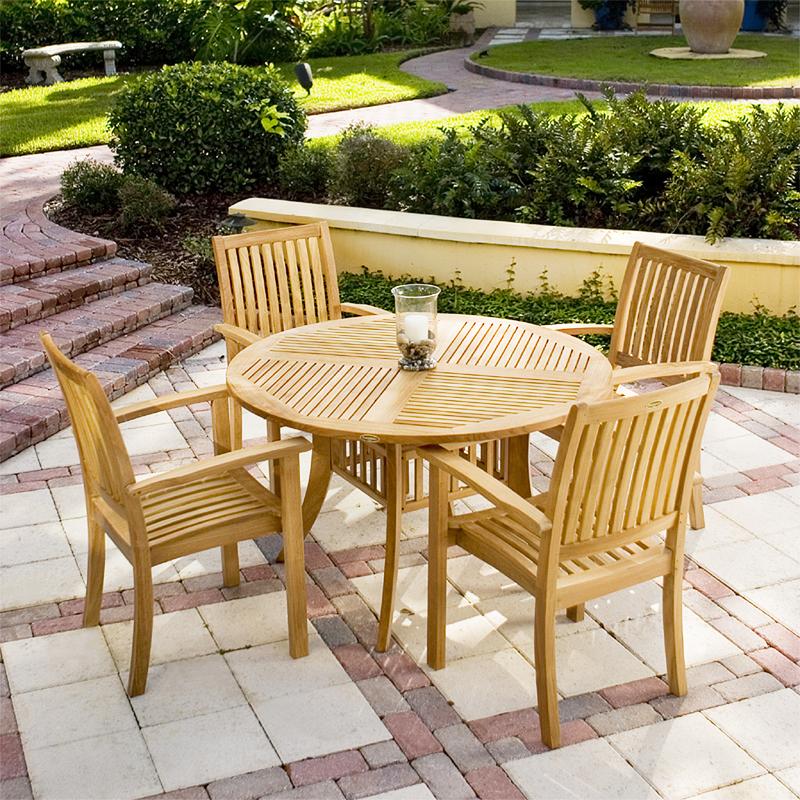 alt="70027 Grand Hyatt 5 piece Dining Set with candle and glass holder on table on brick patio in front of concrete planter of landscape plants a walkway with grass and shrubs in background"