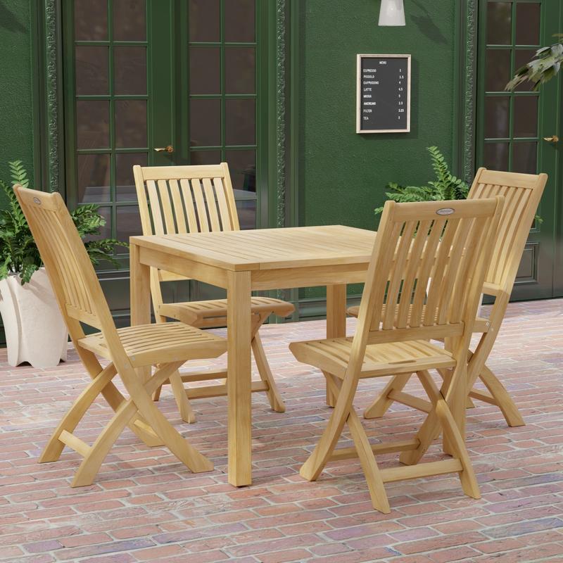 alt="70570 Barbuda 5 pc Dining Set of Barbuda Bistro Teak 36 inch Square Dining Table and 4 Barbuda Folding Chairs side angled view on brick paver patio with door and window of building in background"