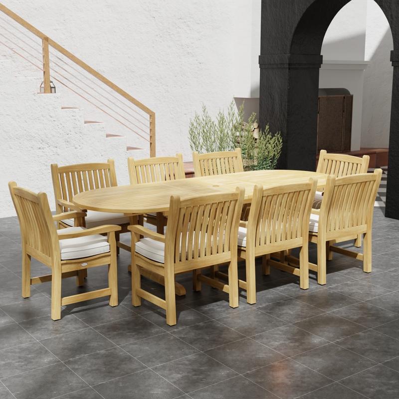 alt="70178 Montserrat Veranda Teak 9 pc Dining Set side angled view on outdoor patio with potted plant and staircase of house and black archway in the background"