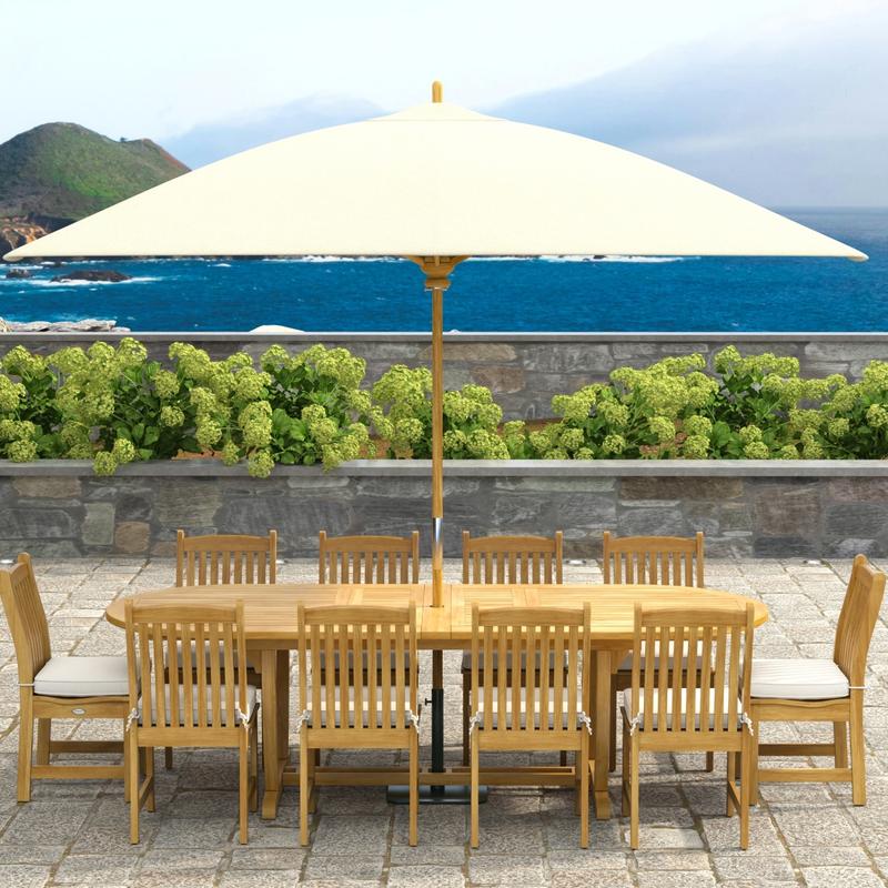 alt="70166 Montserrat Veranda 11pc Dining Set with optional Umbrella and cushions on patio in side view with pergola with stone planter with plants and ocean view in background"