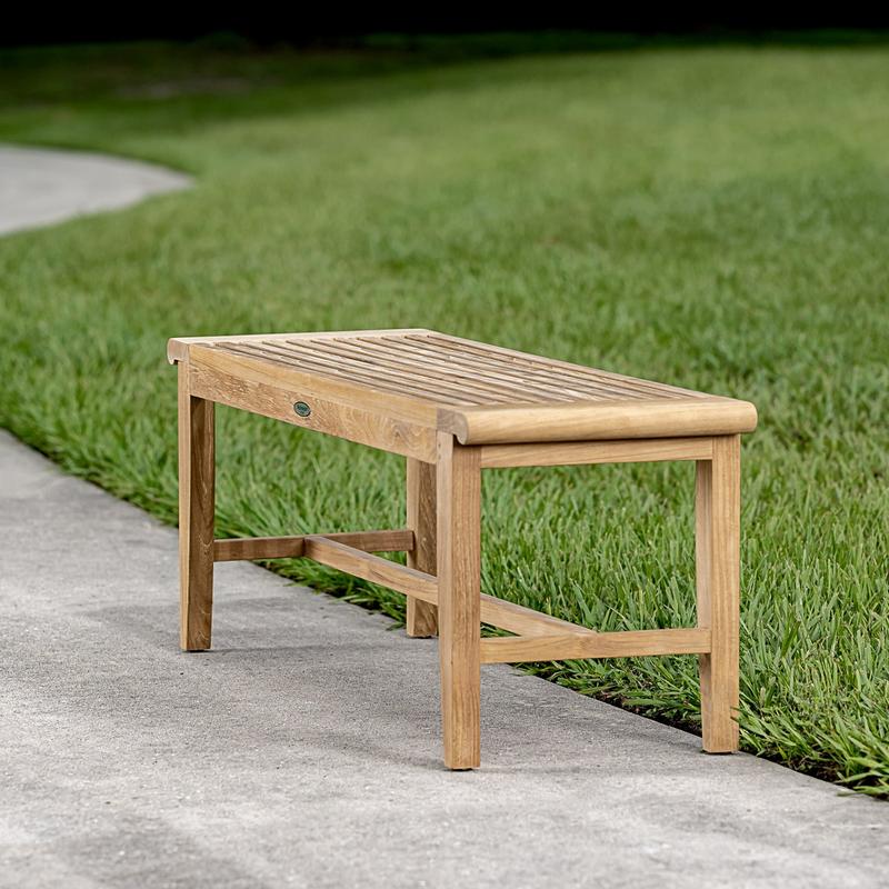 alt="13915 Laguna 4 foot long teak Backless Bench angled end view on concrete walkway with grass in background"