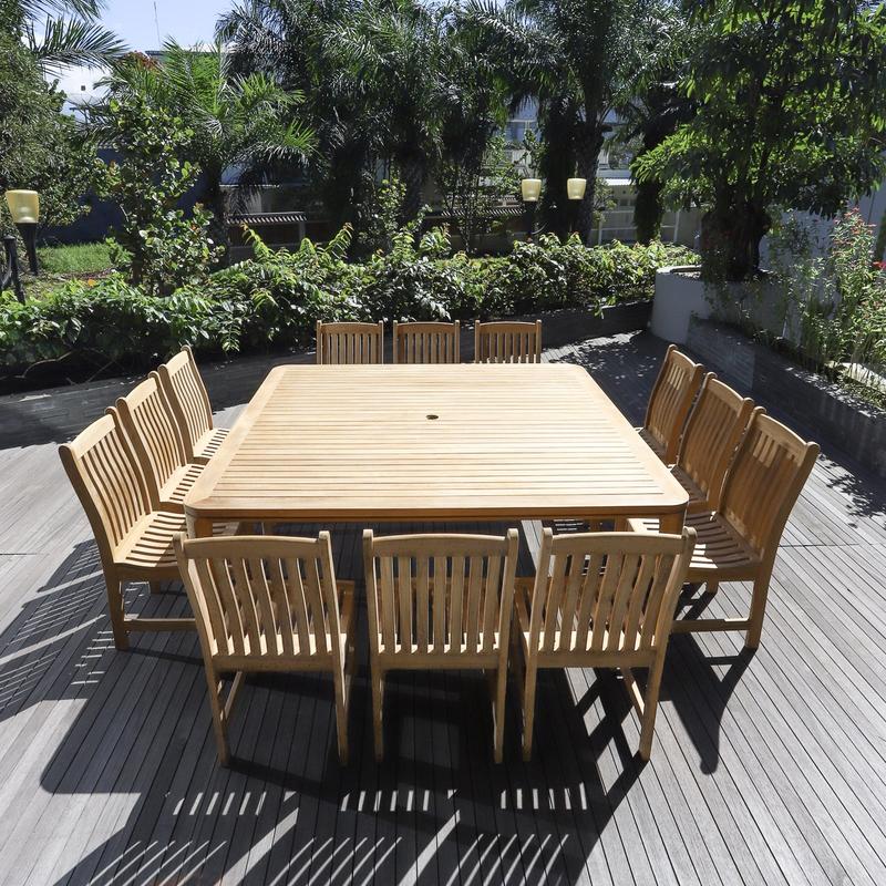 alt="70879 Veranda 13 piece teak Square Dining Set of 12 teak side chair and 6 foot square dining table on wood deck with 4 lamp posts palm trees landscape plants and shrubs in background"