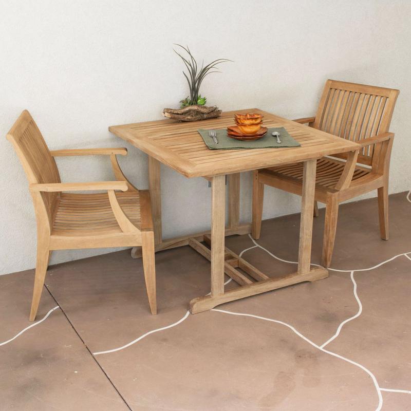 alt="70654 Laguna Square 3 piece teak Dinette Set showing plant and 2 plates and 2 bowls a fork and spoon set on stone patio against a wall "